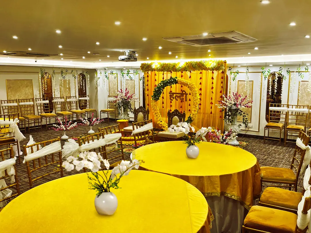 Banquet hall decorated for a family function with yellow drapes and a floral stage